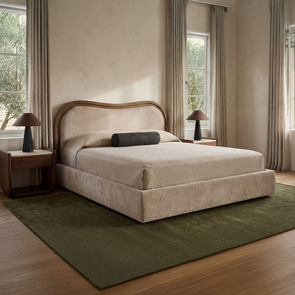 Beige upholstered king bed with arched headboard, gray and dark pillows