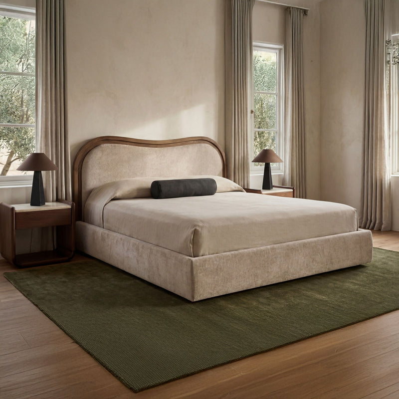 Beige upholstered king bed with arched headboard, gray and dark pillows