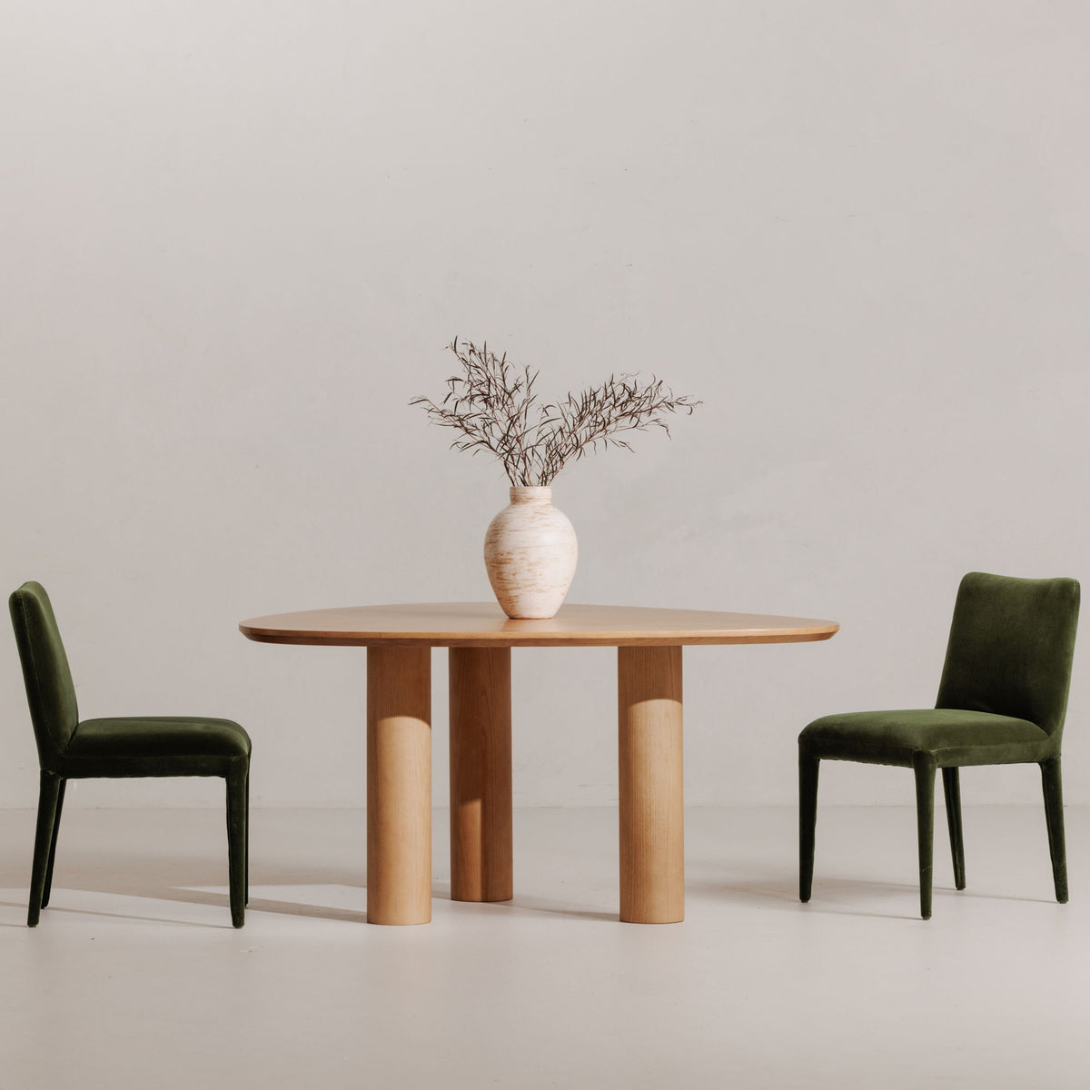 Two green velvet dining chairs with tall square backs and tapered legs