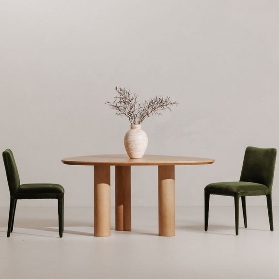 Two green velvet dining chairs with tall square backs and tapered legs