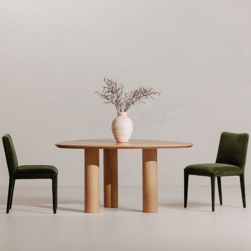 Two green velvet dining chairs with tall square backs and tapered legs