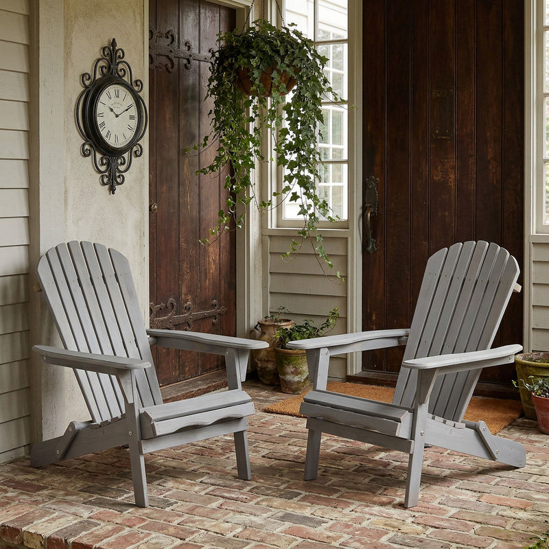 Two folding Adirondack patio chairs in dark gray wood, slatted backs and armrests