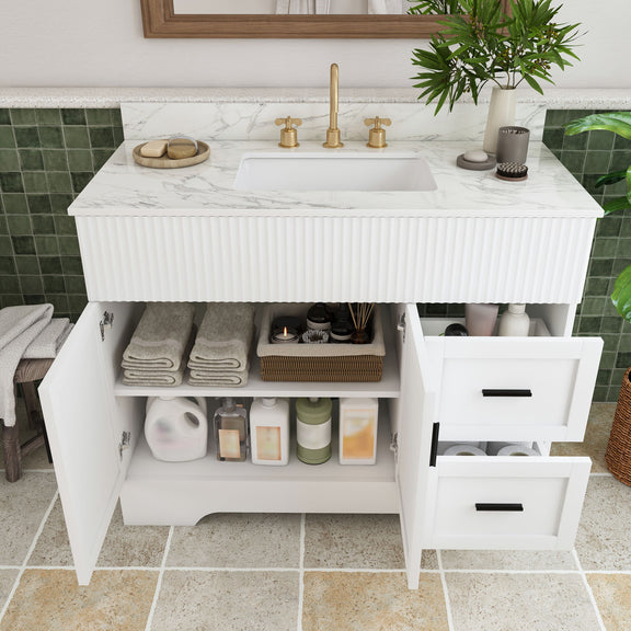 White bathroom vanity with open cabinet and drawer storage, fluted front, and sink top