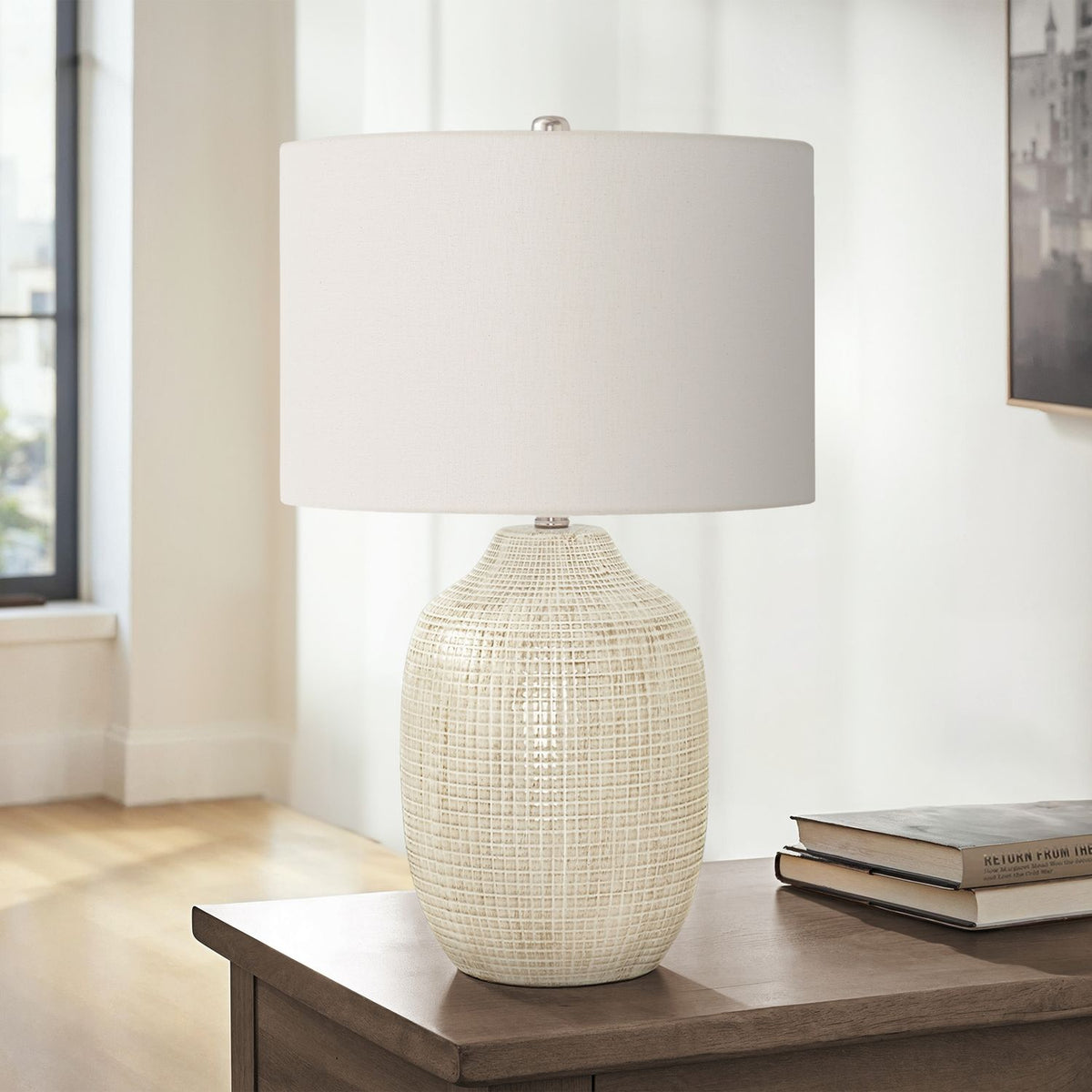 Cream ceramic table lamp with white drum shade, finial, and textured beige base