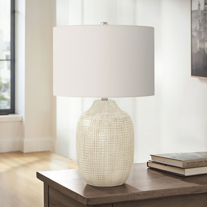 Cream ceramic table lamp with white drum shade, finial, and textured beige base