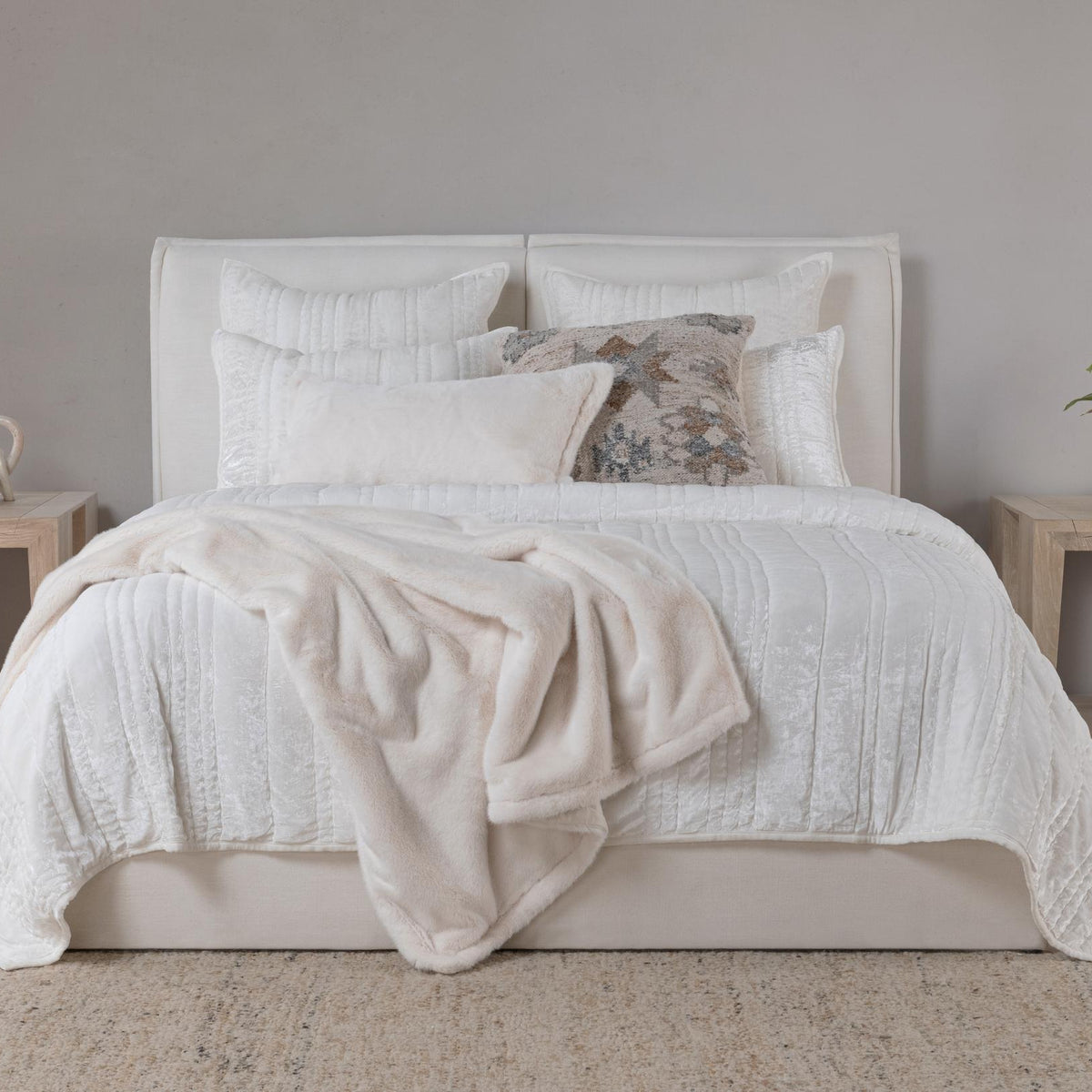 Ivory textured decorative sham pillows behind bed linens