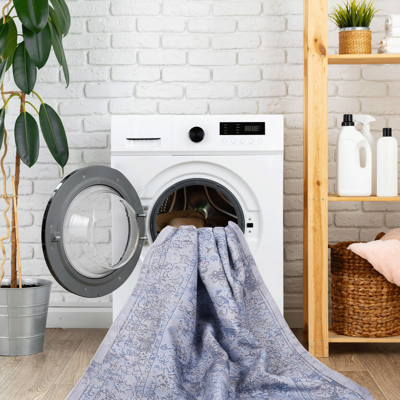 Washable area rug draped over washing machine, light blue with cream abstract pattern