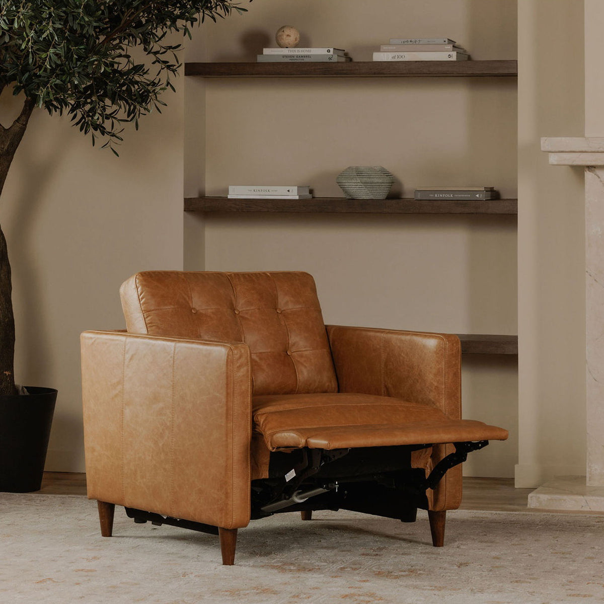 Tan leather recliner chair with footrest extended, showing the reclining mechanism beneath