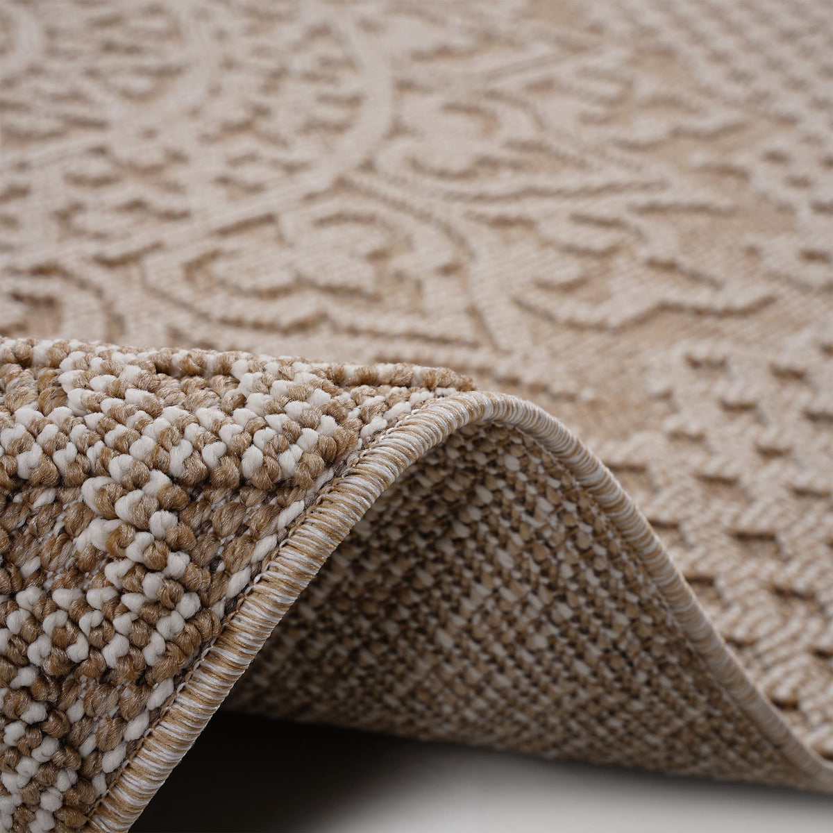 Tan medallion rug close-up with folded edge and thick braided border texture