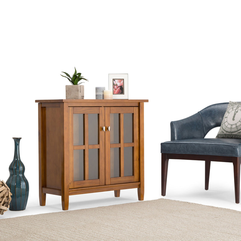 Warm brown wood low storage cabinet with two glass-paneled doors and knobs