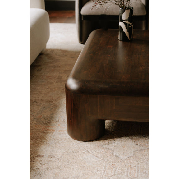 Dark brown wooden coffee table with rounded corner and thick leg detail.