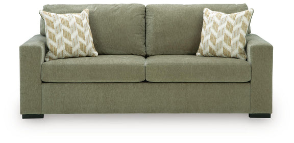 Green fabric sofa with tufted back, two seat cushions, and patterned accent pillows