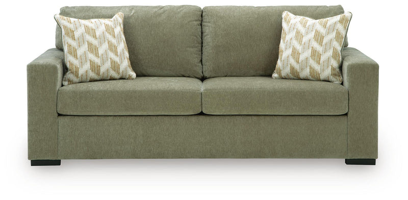 Green fabric sofa with tufted back, two seat cushions, and patterned accent pillows