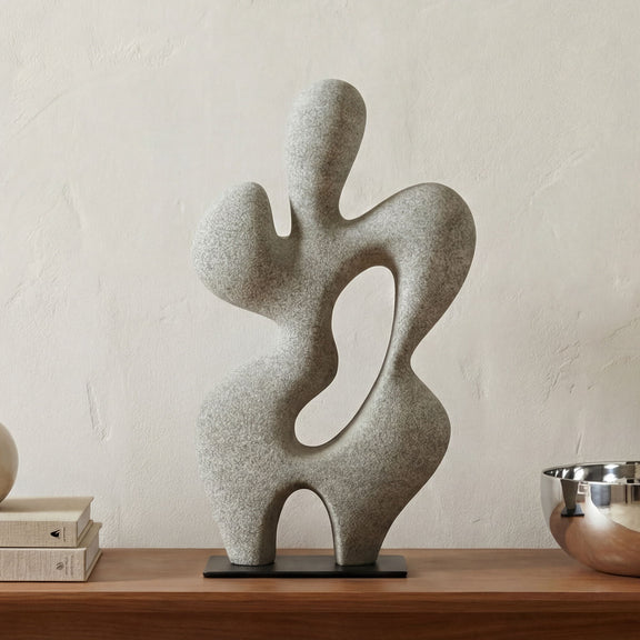 Charcoal gray abstract sculpture with wavy cutouts on black base, on tabletop