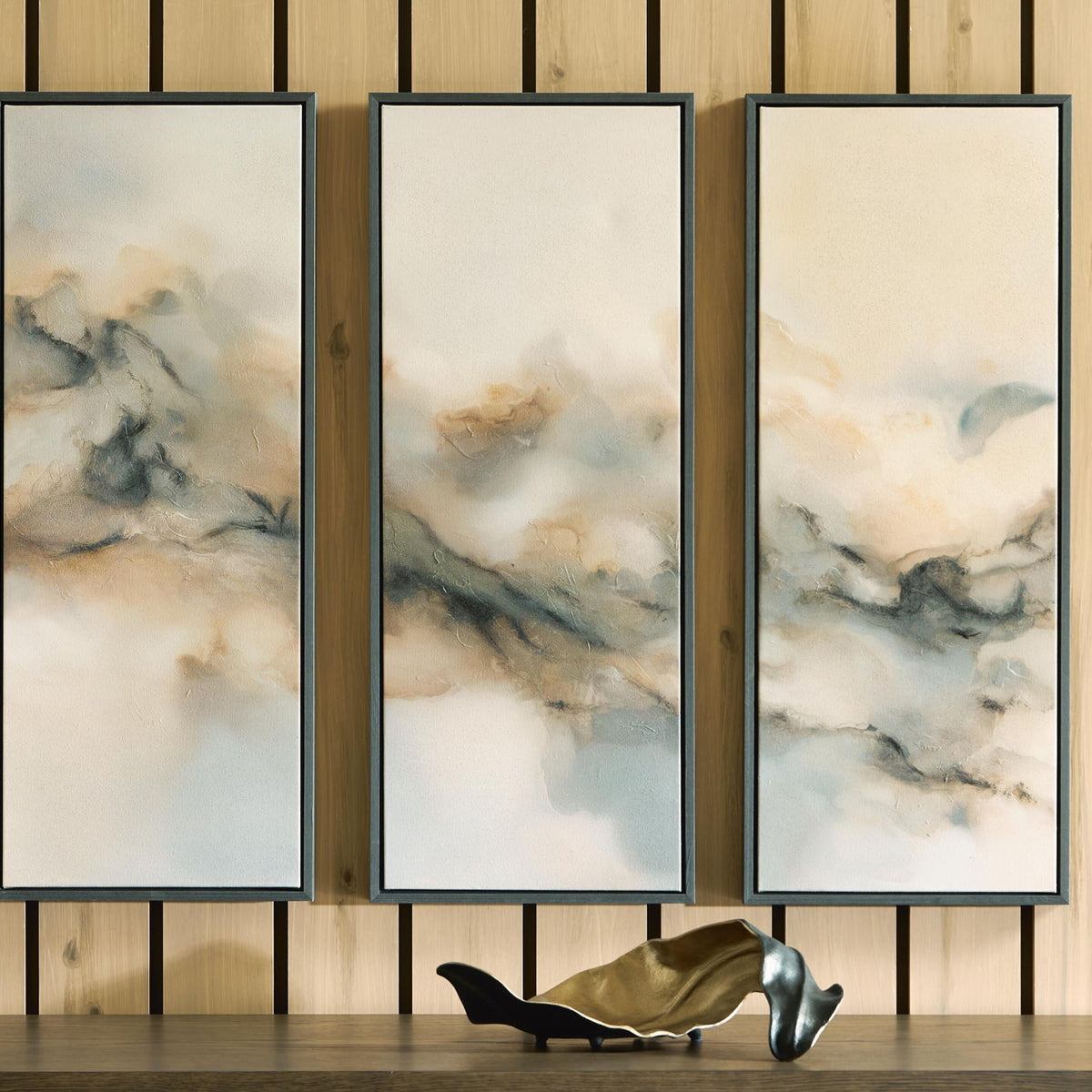 Set of 3 framed abstract landscape wall prints on wall, dark gray frames, cloudy tones