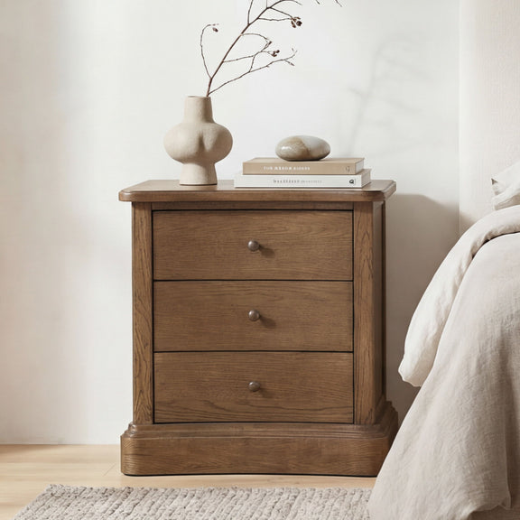 Warm brown wooden nightstand with three drawers and round knob pulls, flat top