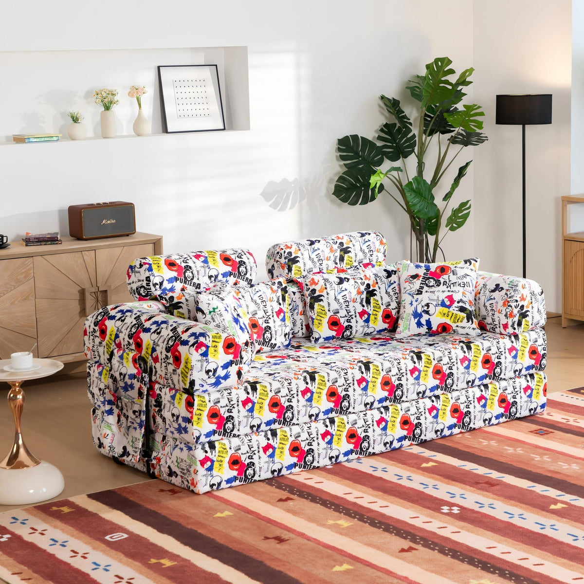 White convertible sleeper sofa with colorful graffiti print upholstery and armrest pillows