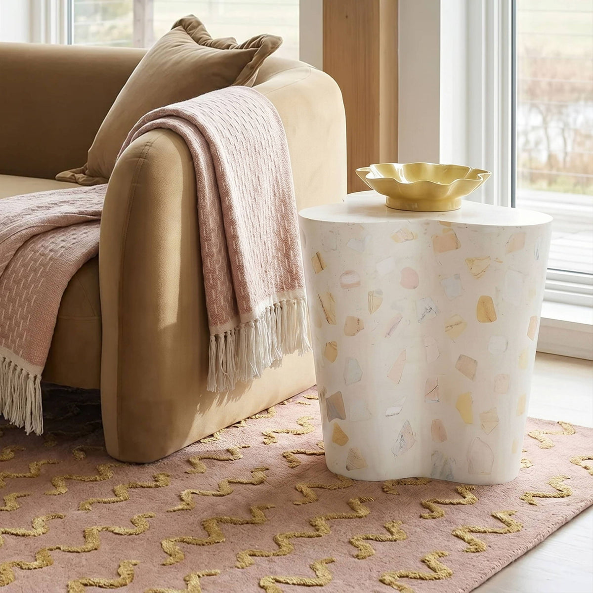 Beige terrazzo-pattern side table with rounded top and sturdy, curved base