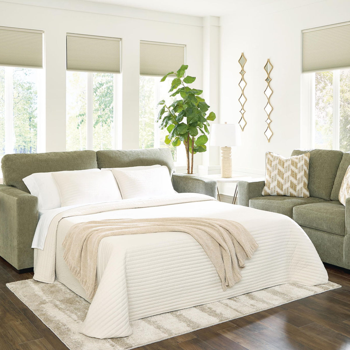 Green sofa sleeper with bed extended, white bedding and striped throw blanket