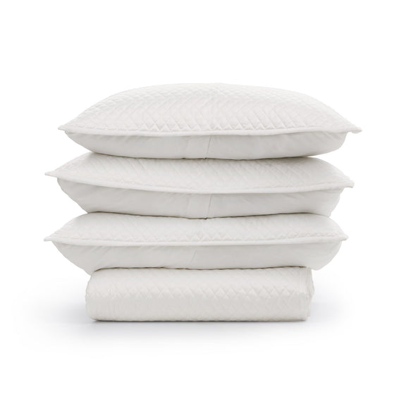 Stack of quilted white throw pillow shams with diamond pattern texture