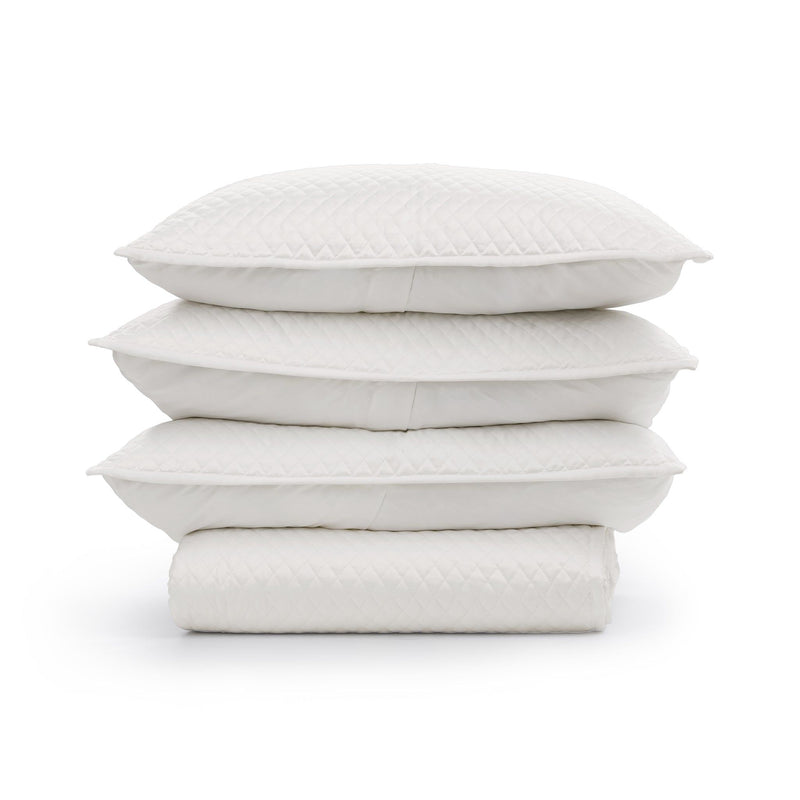 White quilt stack with diamond-patterned quilting pillows