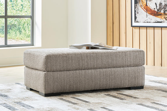 Gray upholstered ottoman with stitched cushion and black base feet