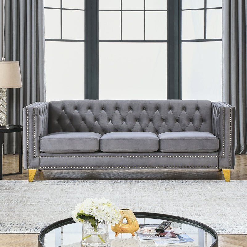 Dark gray button-tufted sofa with nailhead trim, three seat cushions, and gold legs