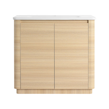 Freestanding bathroom vanity with white sink top and light brown two-door cabinet