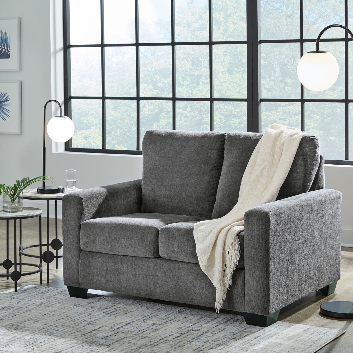 Dark gray fabric sofa with square arms, three seat cushions, and a light throw blanket