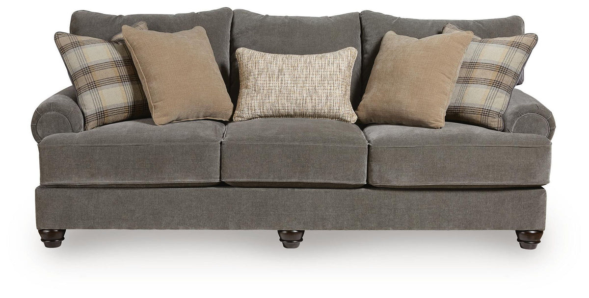Dark gray sofa with three seat sections, rolled arms, and plaid and solid beige pillows