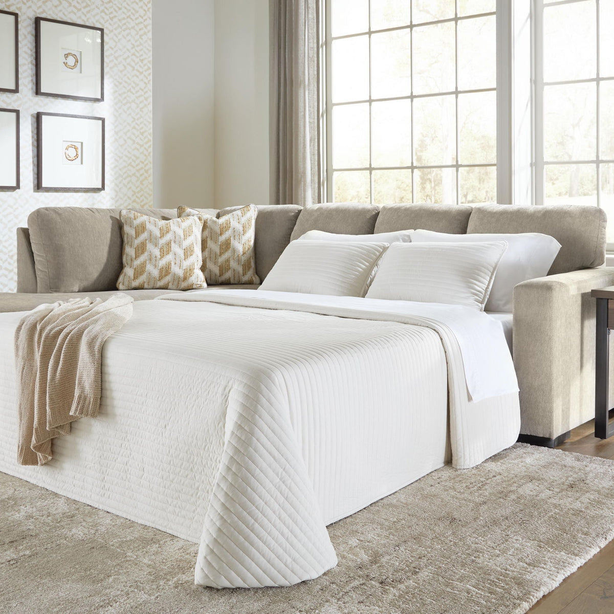 Gray sleeper sectional sofa opened into bed with white comforter and throw