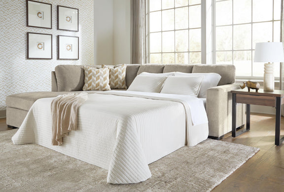 Gray sleeper sectional sofa opened into bed with white comforter and throw