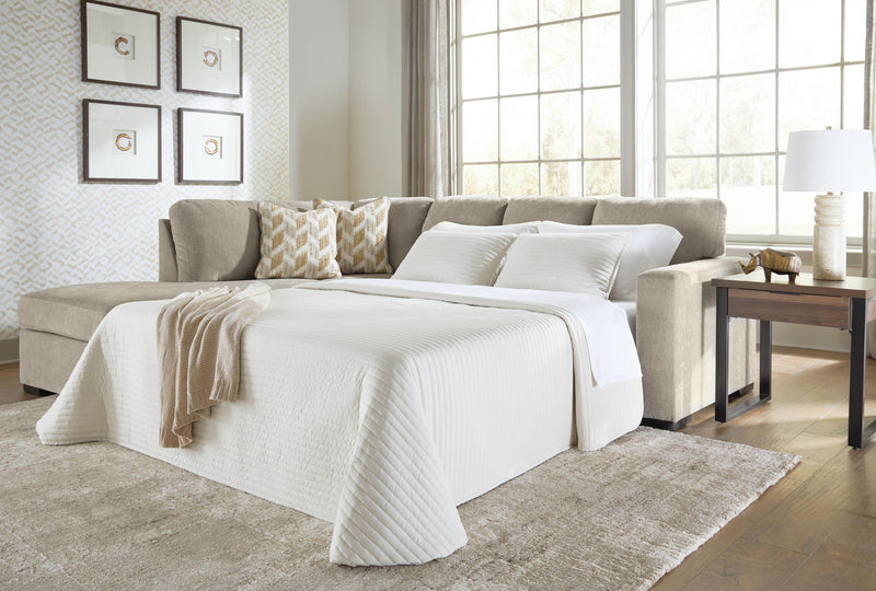 Gray sleeper sectional sofa opened into bed with white comforter and throw