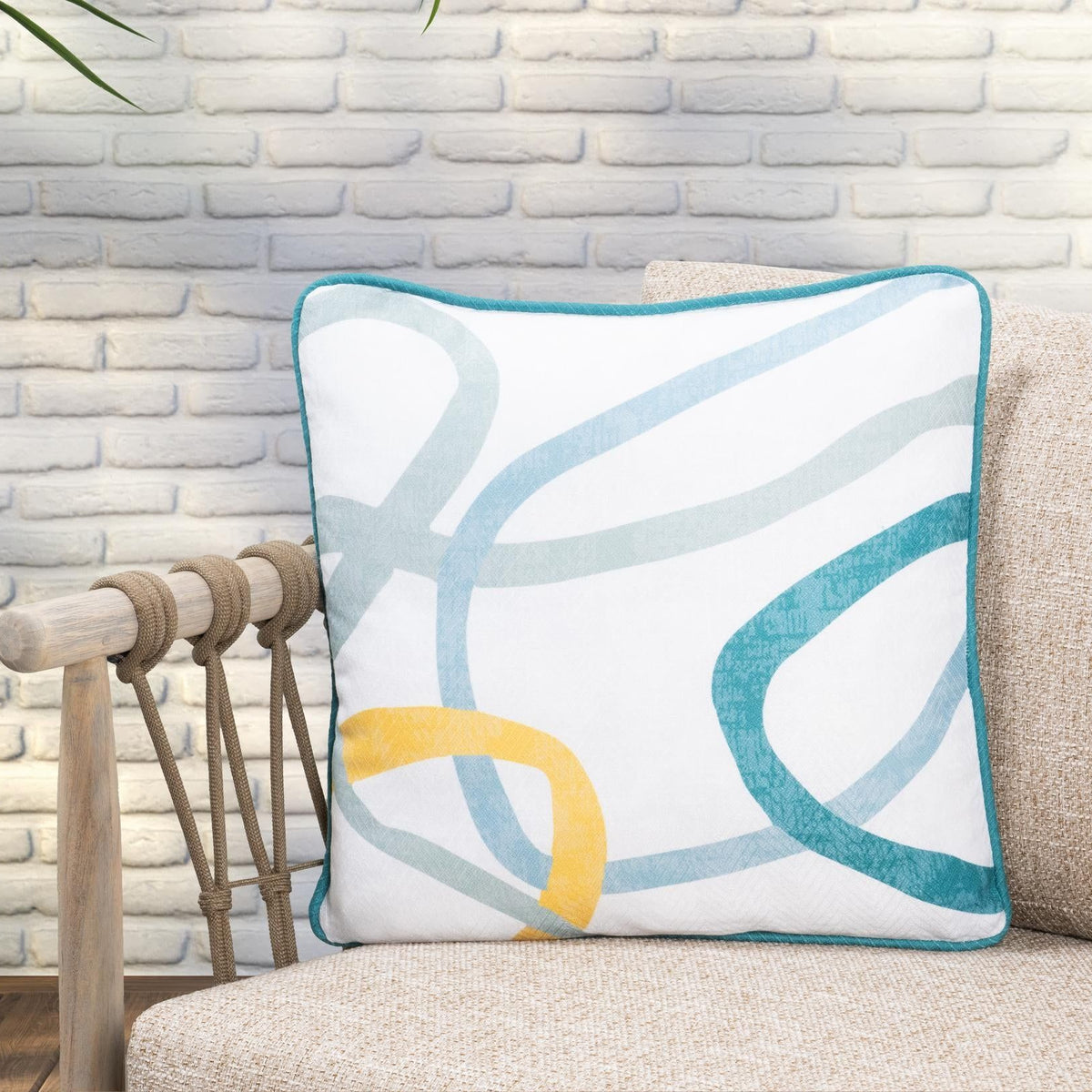 Square throw pillow with white base and teal/blue/yellow abstract print with teal trim.