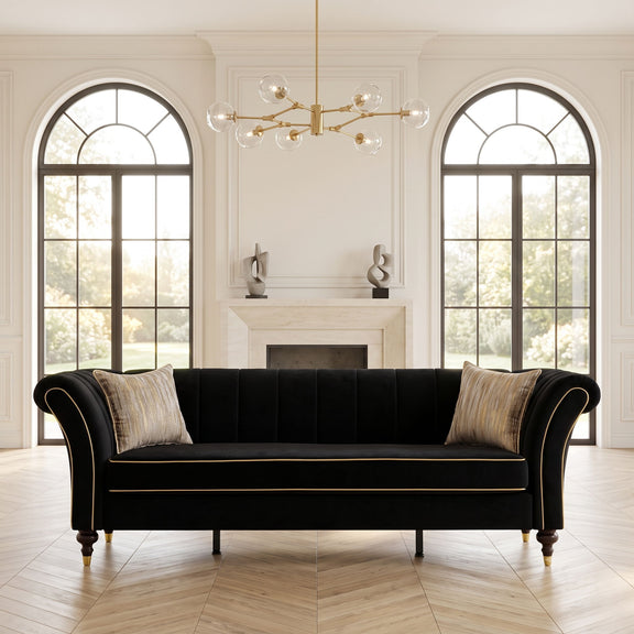 Black three-seat sofa with rolled arms, channel-tufted back, gold piping and two pillows