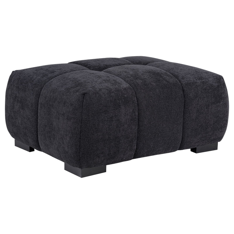 Dark gray rectangular upholstered ottoman with tufted sections and low black legs.