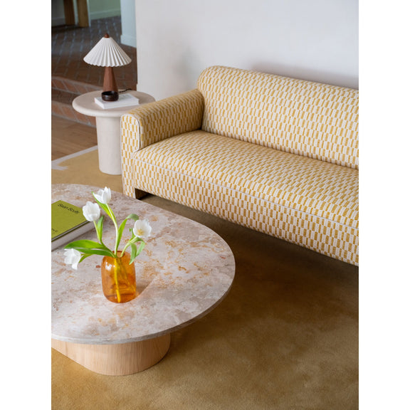 Round coffee table with mottled stone top on curved light wood pedestal base