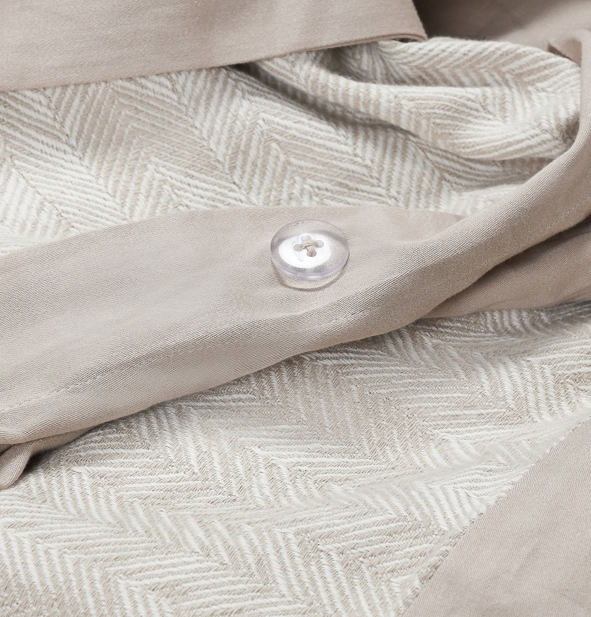 Natural French herringbone duvet close-up with textured chevron weave and fabric button