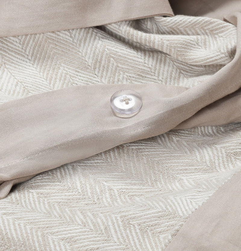 Natural French herringbone duvet close-up with textured chevron weave and fabric button