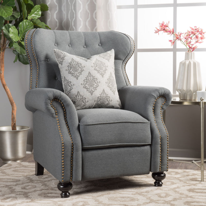 White tufted recliner chair with studded trim and a decorative throw pillow.