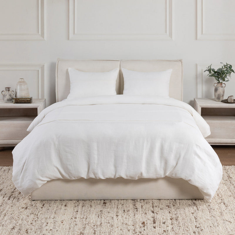 Two white pillow shams with simple stitched edges on a bed