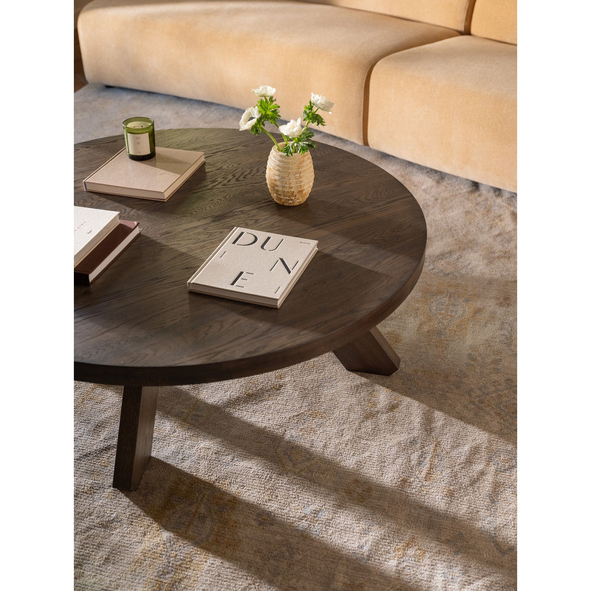 Round dark brown coffee table with wood grain finish and angled support legs