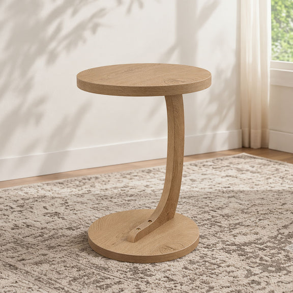 Light brown round end table with pedestal base and lower shelf on carpet