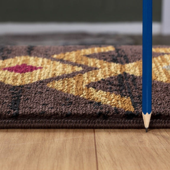 Southwest area rug close-up, dark brown weave with gold geometric pattern and flat edge
