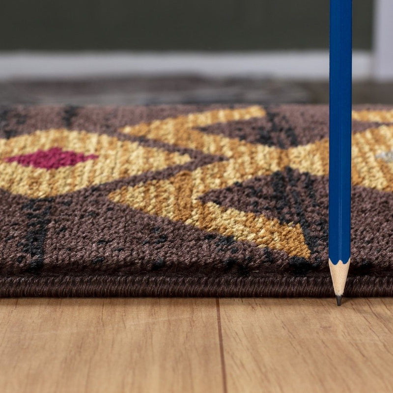 Southwest area rug close-up, dark brown weave with gold geometric pattern and flat edge