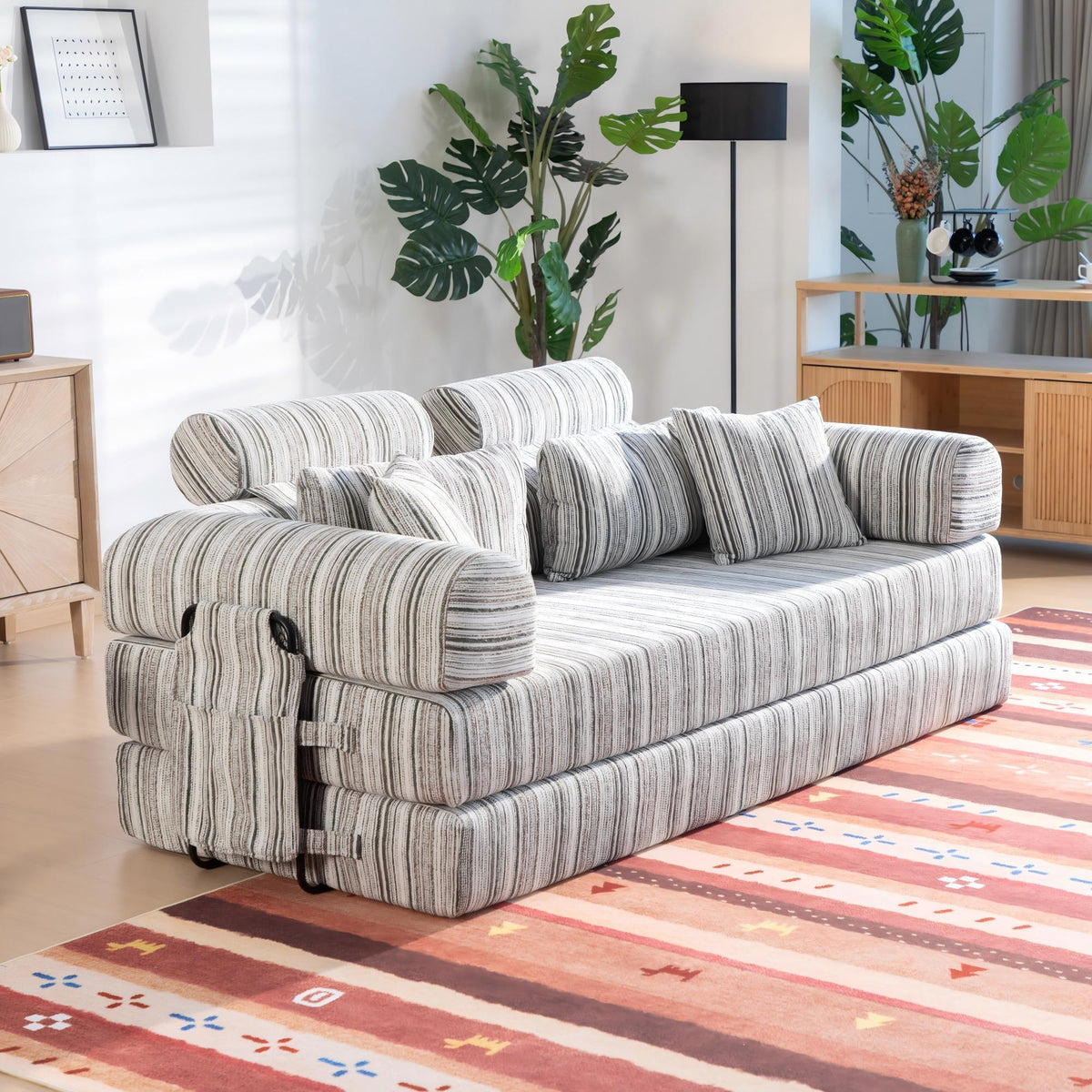 Convertible sofa bed in sleeper position with striped upholstery and side armrest details