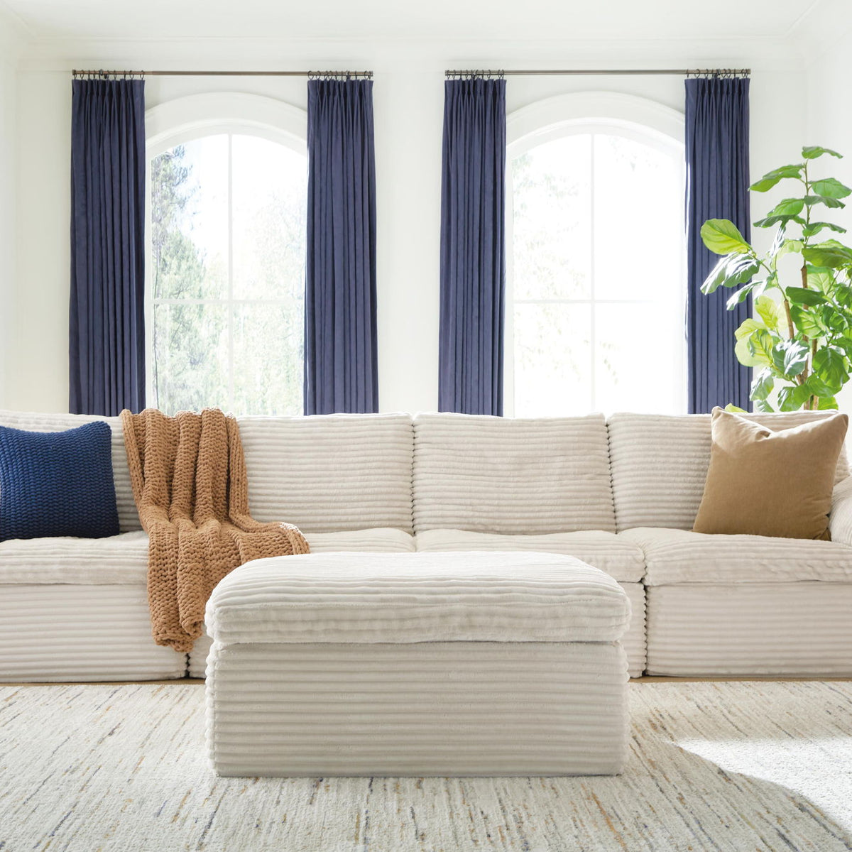 Ivory sectional sofa with ottoman; channel-textured cushions and decorative pillows