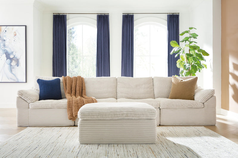 Ivory sectional sofa with ottoman; channel-textured cushions and decorative pillows