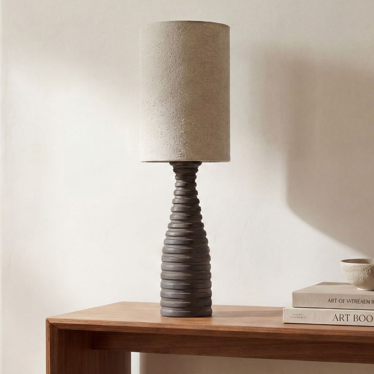 Table lamp featuring a beige fabric drum shade on a dark ribbed base
