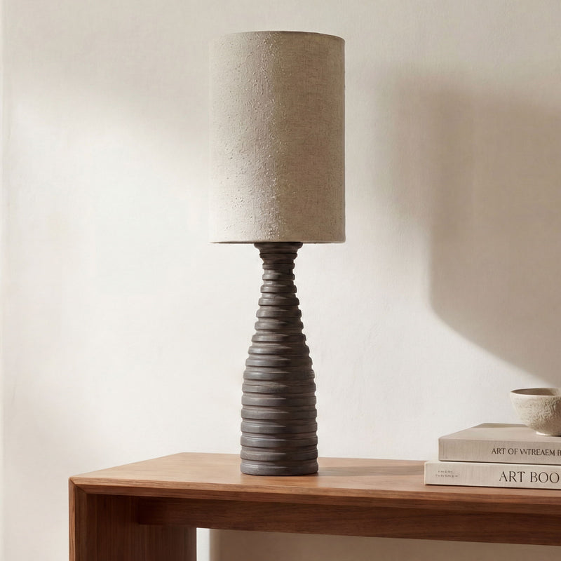 Table lamp featuring a beige fabric drum shade on a dark ribbed base